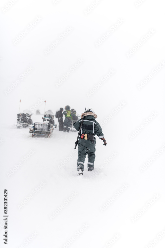 Unrecognizable man walking to travelers with snowmobiles Unrecognizable man walking to travelers with snowmobiles