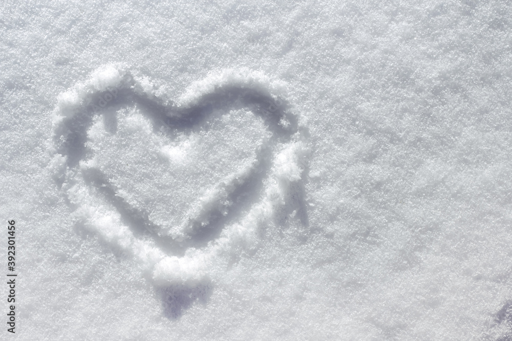 White snow texture on a sunny winter day. A heart drawn in the snow copy space.