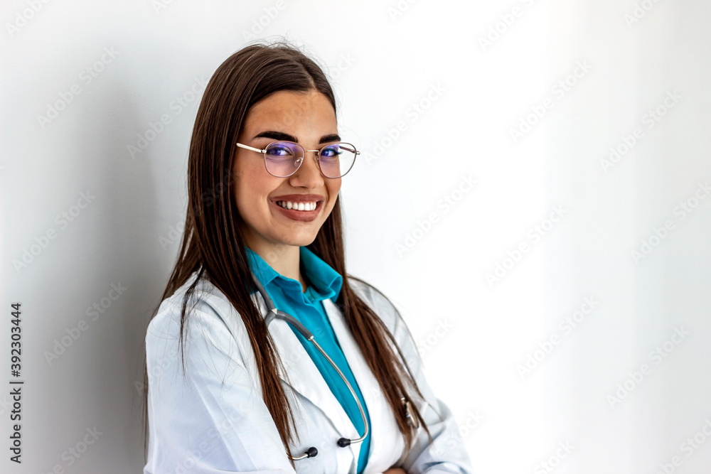 Cropped shot of an cheerful female doctor wearing glasses and smiling towards camera. Pretty young adult Caucasian surgeon smiles cheerfully at the camera. She is wearing a stethoscope and lab coat. Cropped shot of an cheerful female doctor wearing glasses and smiling towards camera. Pretty young adult Caucasian surgeon smiles cheerfully at the camera. She is wearing a stethoscope and lab coat.