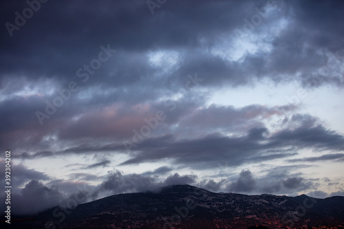 Heavy dark clouds on sky over mountains background, sunrise