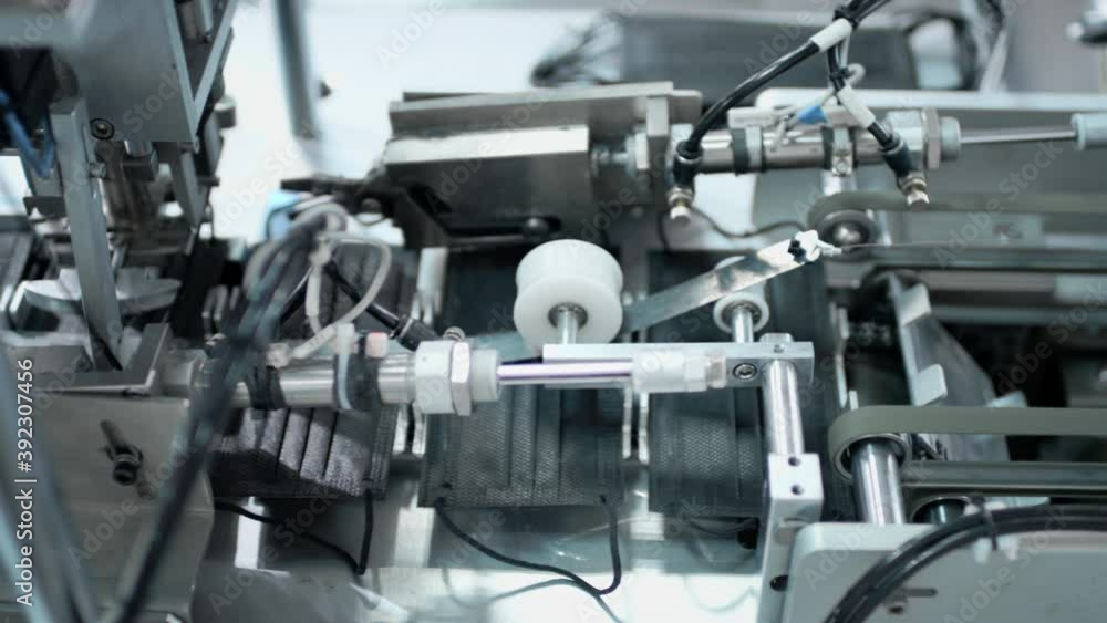 Production of medical three-layer black masks. Manufacturing of protective face masks during the coronavirus pandemic. The plant makes face masks for the virus. The machine creates clothes for doctors Production of medical three-layer black masks. Manufacturing of protective face masks during the coronavirus pandemic. The plant makes face masks for the virus. The machine creates clothes for doctors