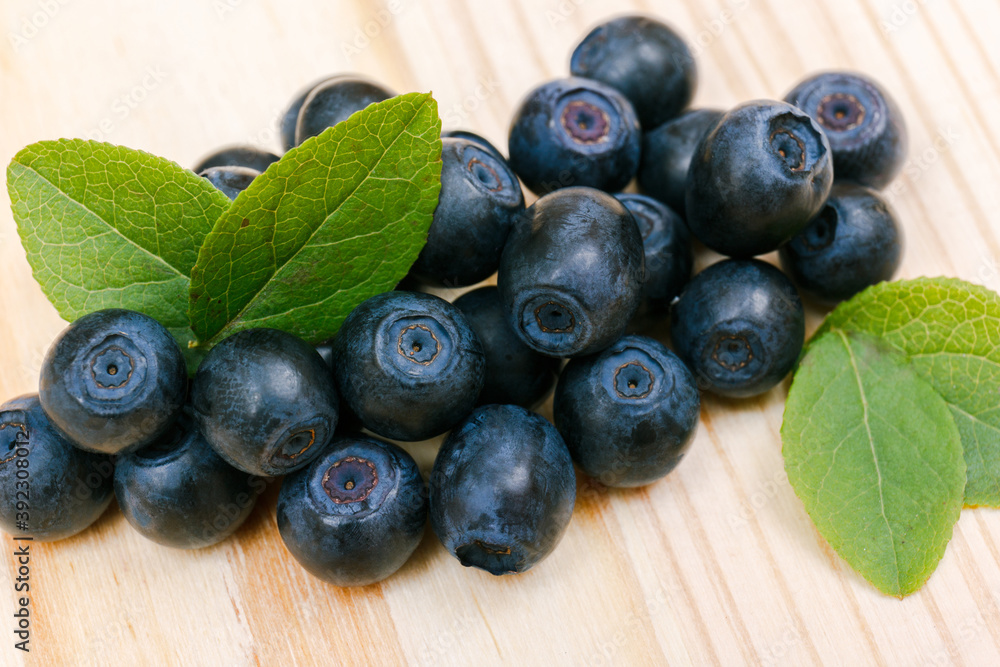A heap of bilberries on a wooden table. Bilberry leafs. Macro shot. A heap of bilberries on a wooden table. Bilberry leafs. Macro shot.