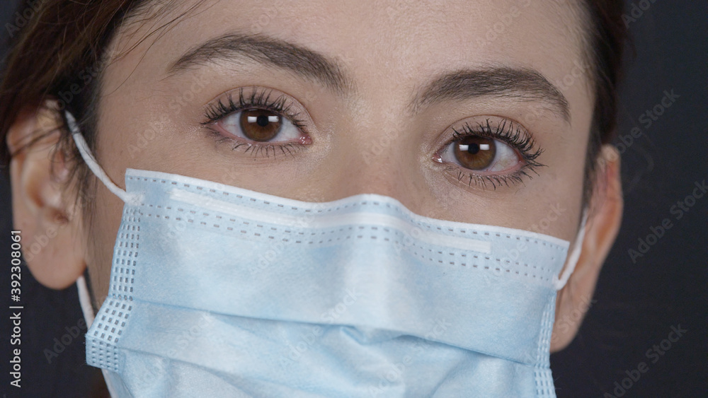 Girl with pretty eyes wearing face mask looking at the camera after raising her head. Girl with pretty eyes wearing face mask looking at the camera after raising her head.