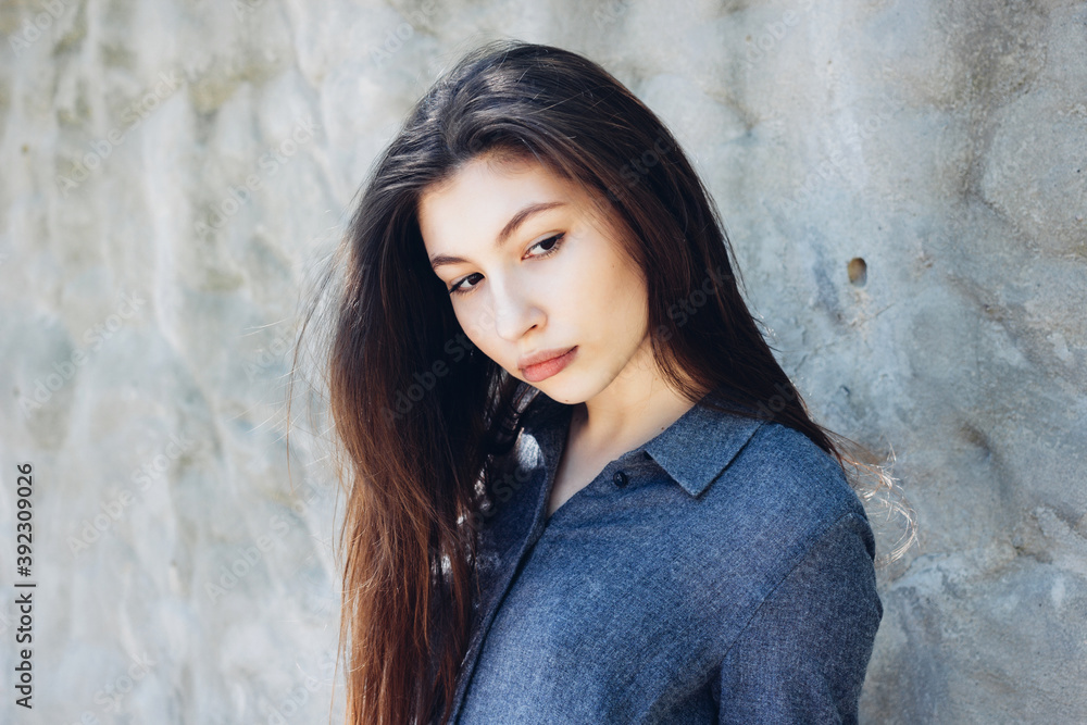 Portrait of young stylish girl in front of white concrete wall in sunny day. Portrait of beautiful girl. Pretty girl with long dark hair and red lips. Portrait of young stylish girl in front of white concrete wall in sunny day. Portrait of beautiful girl. Pretty girl with long dark hair and red lips.