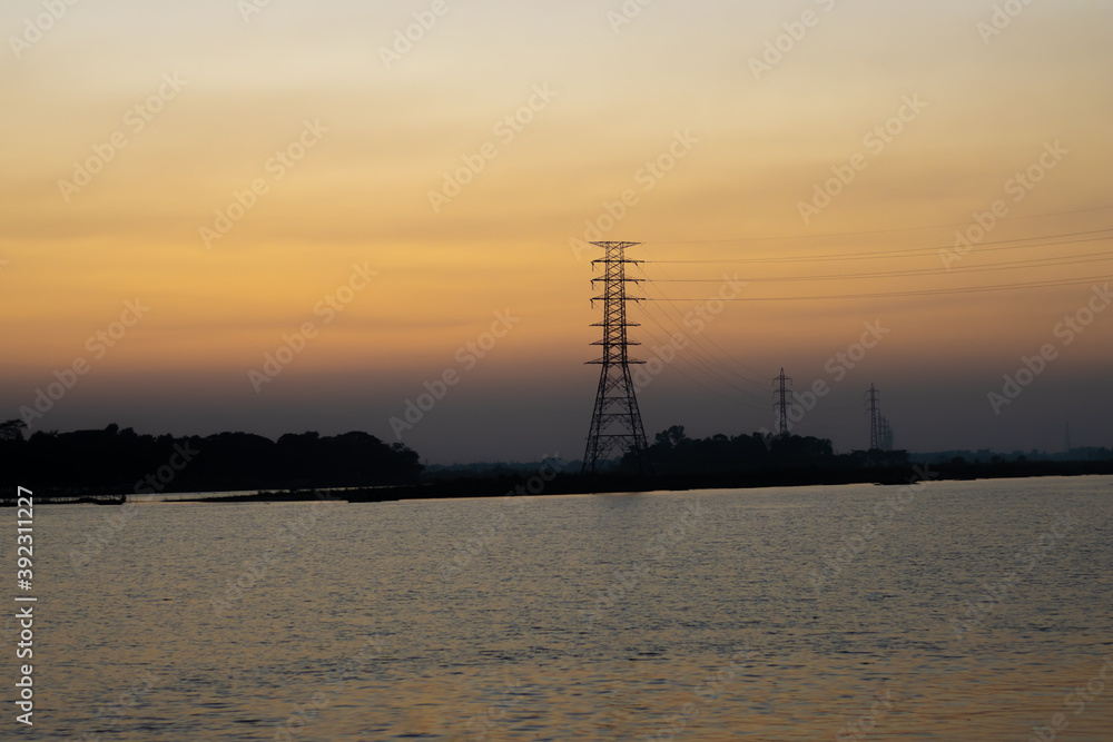 High voltage power lines on the river at the evening