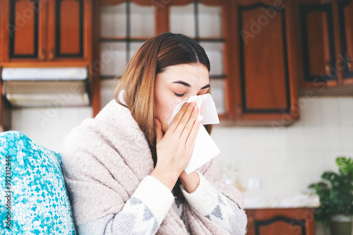 Sick young woman wipes her nose with a handkerchief