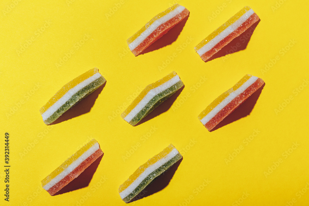 Set of colorful triangular jelly candy lined up on yellow background. Multi-colored marmalade jelly candy's. Top view. Set of colorful triangular jelly candy lined up on yellow background. Multi-colored marmalade jelly candy's. Top view.