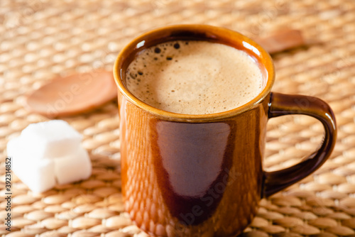Taza de arcilla con café caliente sobre fondo rústico