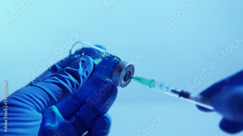 Hand of scientists in blue gloves holding vial with safe and effective vaccine against virus. Concept of research and approval of cure in the laboratory.