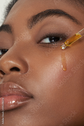 Model with face serum dripping on face photo
