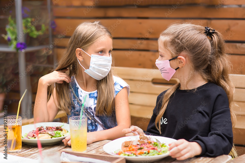 Cute children with face mask is having food in restaurant, New normal concept.