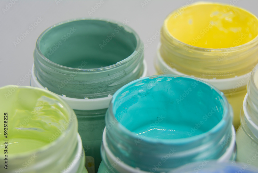 Jars of acrylic paint in green, blue, yellow shades close-up. Jars of acrylic paint in green, blue, yellow shades close-up.