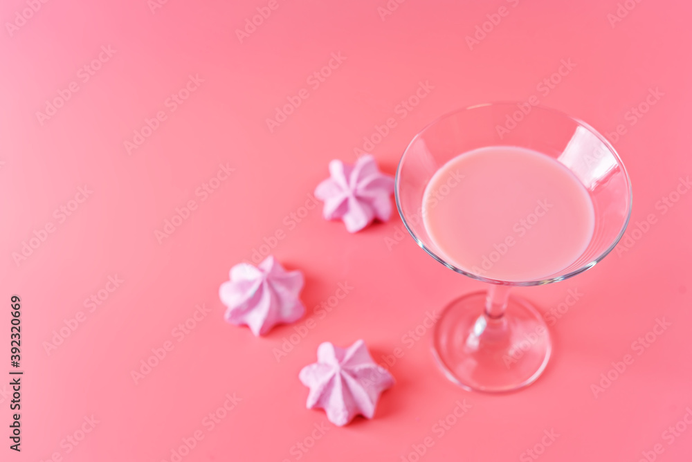 Pink milk cocktail in a glass with merengue cookies