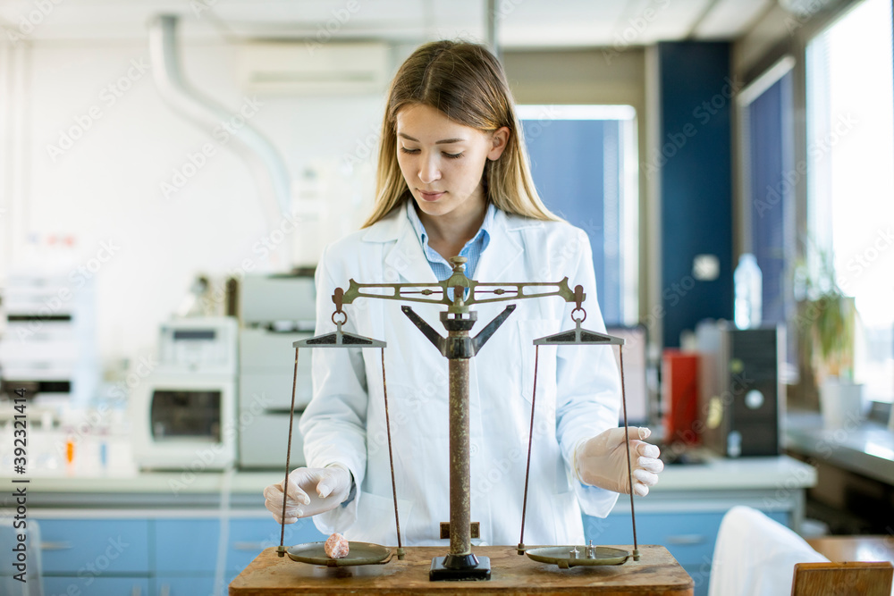 Young female researcher measuring weight of the mineral sample in the lab Young female researcher measuring weight of the mineral sample in the lab