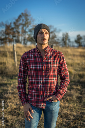 portrait of a 30 year old man in a red checkered shirt and gray wool hat