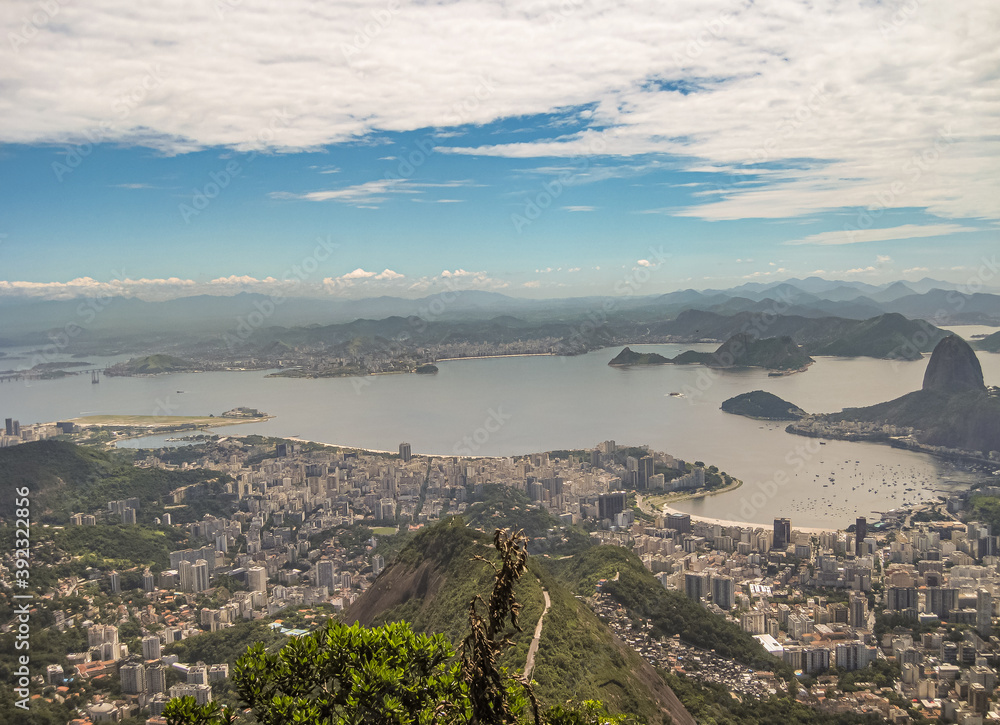 Rio de Janeiro, Brazil - December 24, 2008: Aerial view of bay from entrance to port and beyond. Tall buildings in many neighorhoods under blue cloudscape and mountains in distance.