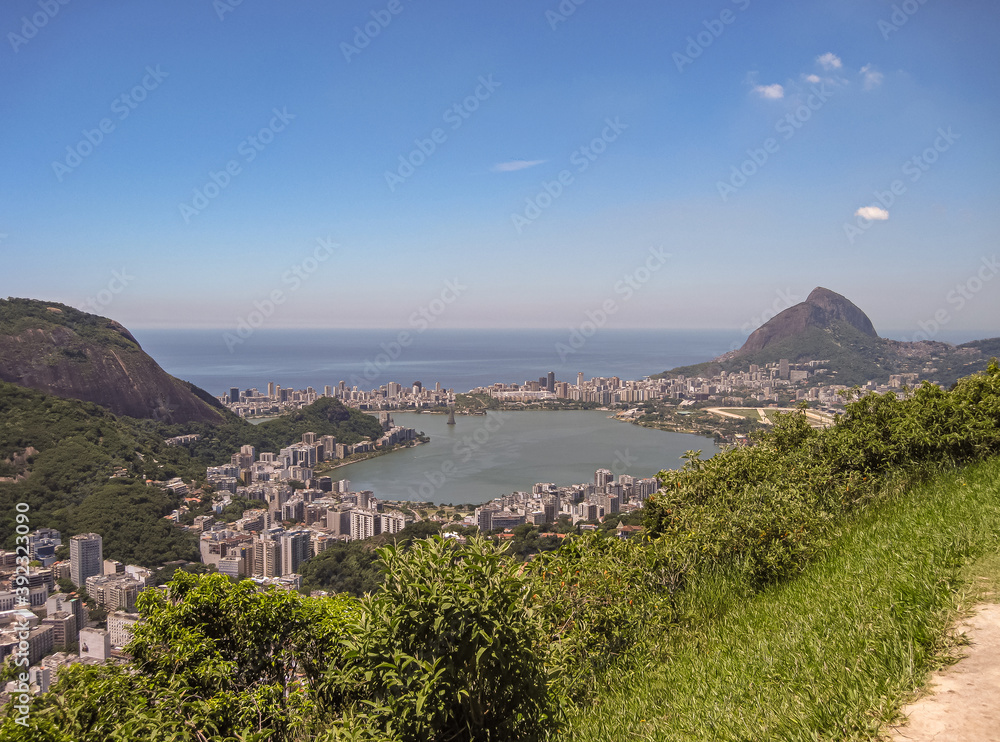 Fototapeta premium Rio de Janeiro, Brazil - December 24, 2008: Wide Aerial view of green Lagoa Rodrigo de Freitas and Lagoa, Leblon, and Ipanema neighborhoods up to blue ocean. Islands and Christmas tree. Foliage up fro