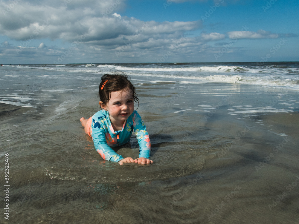 Little girl laying in the water at the beach. Stock Photo | Adobe Stock