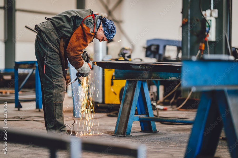 Worker Using Angle Grinder in Factory