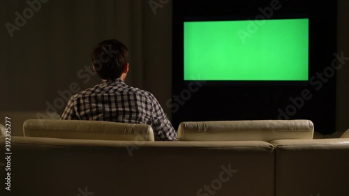 Man watches a green screen TV and drinks tea