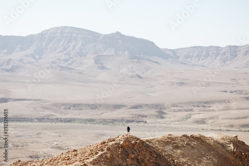 A man hiking alone on top of a mountain in the hot desert wilderness 