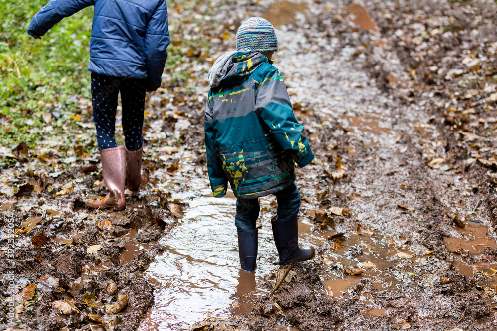 Two children wearing wellies walking through deep mud. Two children wearing wellies walking through deep mud.