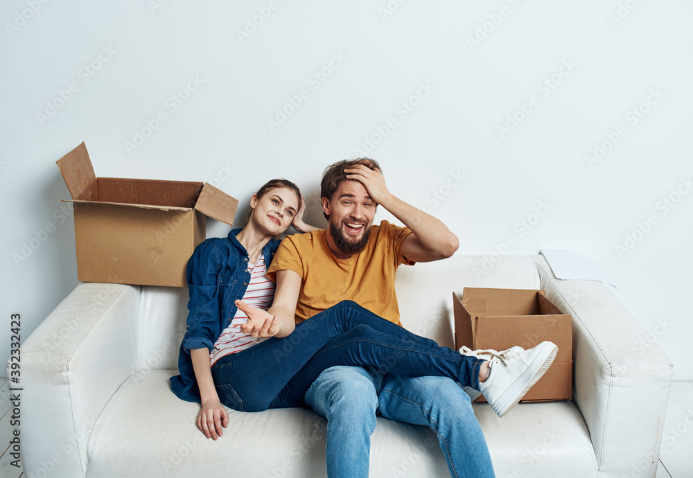 Emotional young couple on the couch with cardboard boxes interior Emotional young couple on the couch with cardboard boxes interior