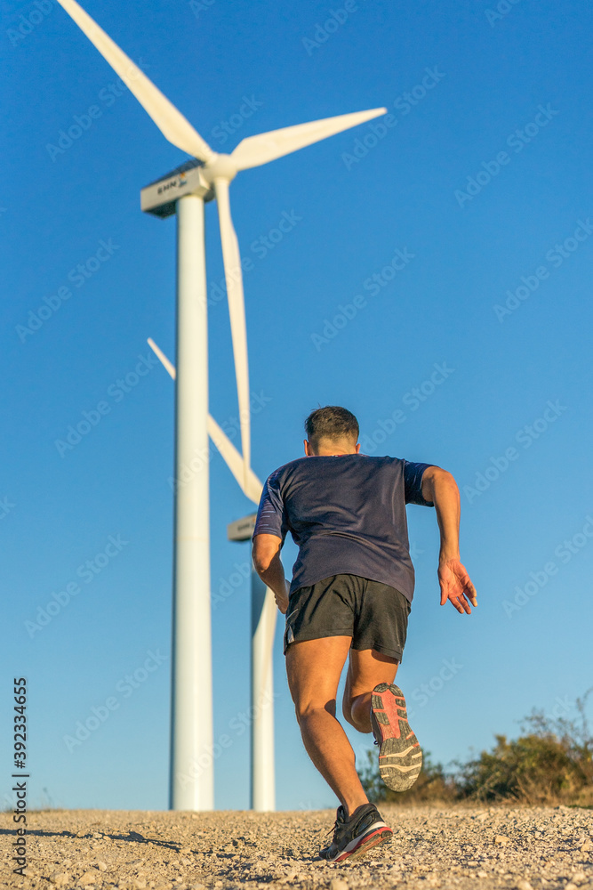 rear view of a man running between windmills