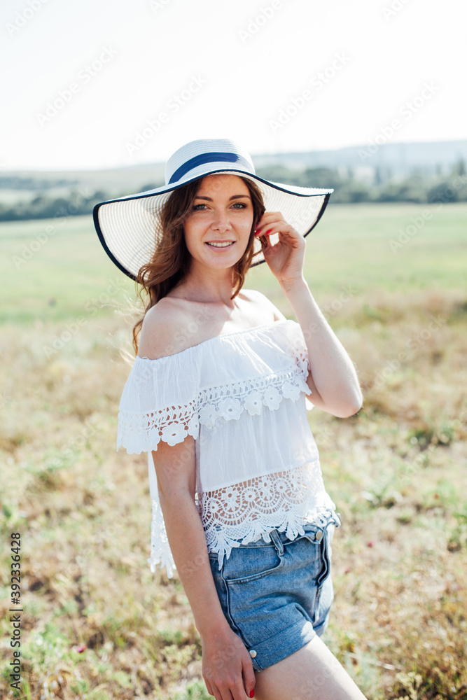 portrait of a beautiful woman in a hat with fields in nature in a field