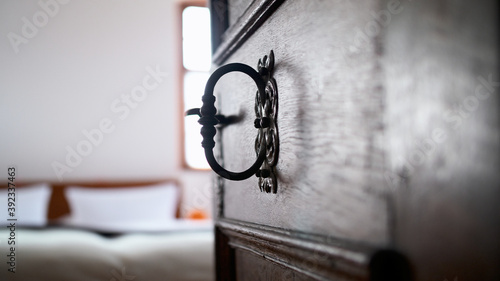 Old wooden brown door with iron mountings. Door wide open with a view on the hotel bed