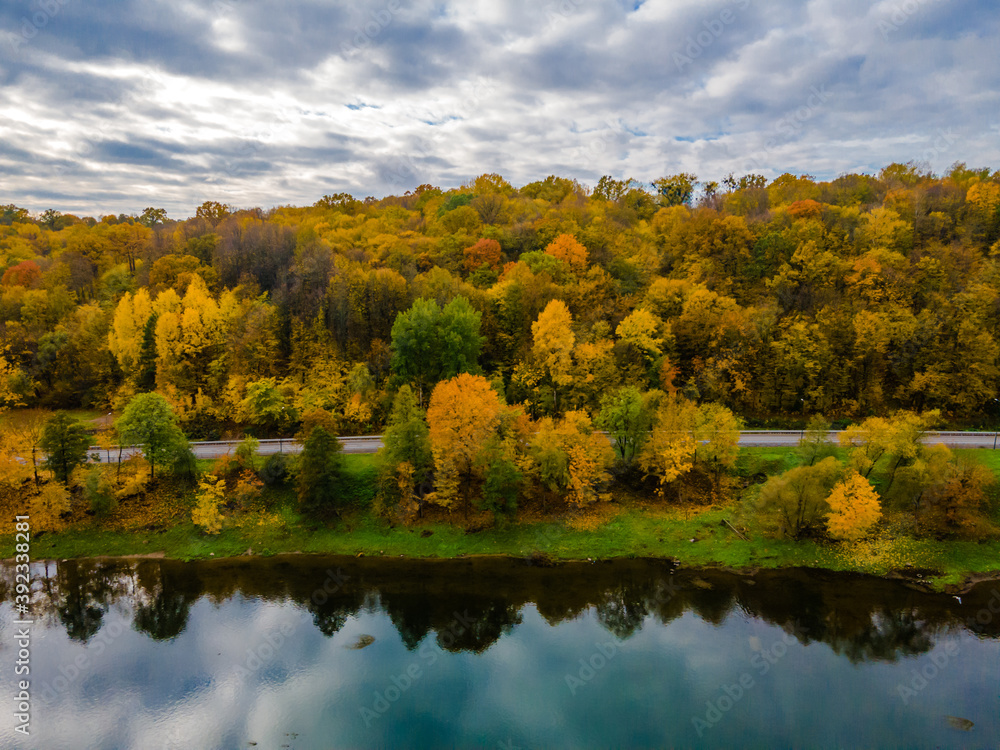 Fototapeta premium Aerial autumn view of a hill with golden trees and reflections in river