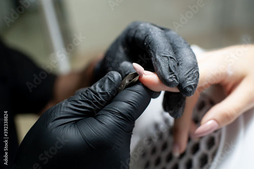 Manicurist cuts a long  broken nail on a woman s hand