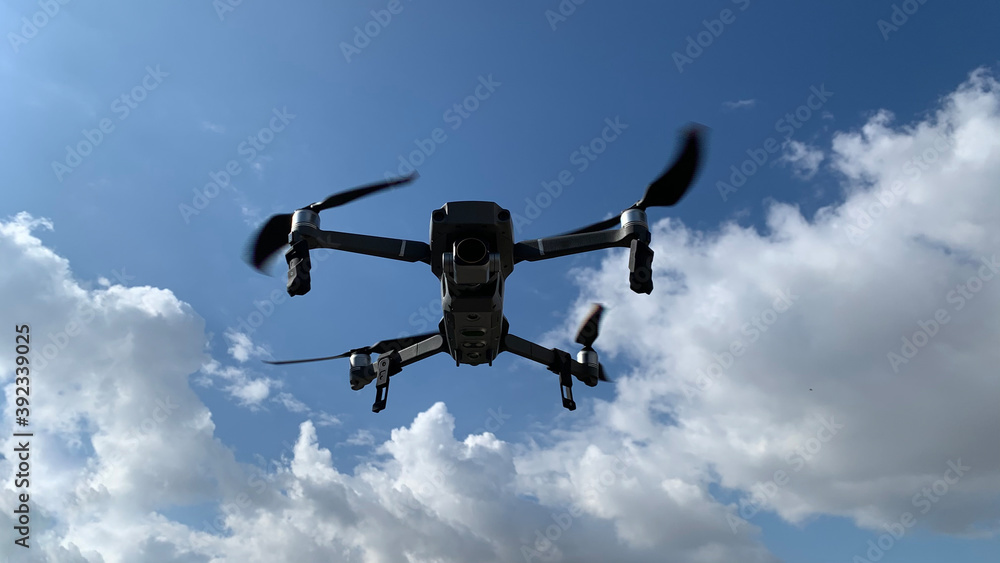 Latest technology RC camera drone or UAV (unmanned aerial vehicle) hovering on deep blue cloudy sky Latest technology RC camera drone or UAV (unmanned aerial vehicle) hovering on deep blue cloudy sky