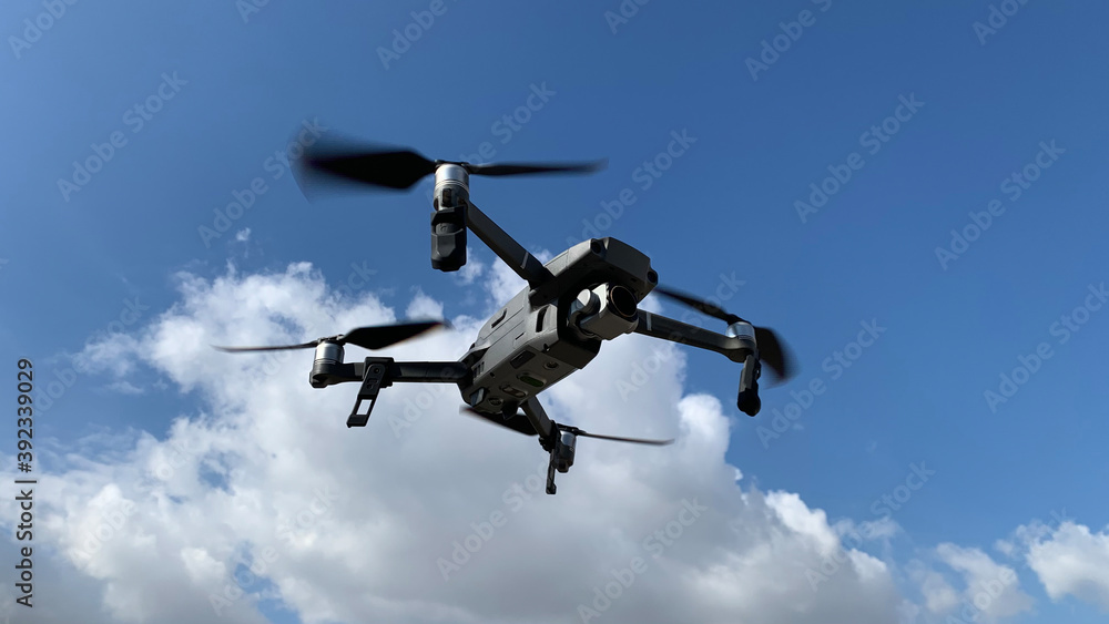 Latest technology RC camera drone or UAV (unmanned aerial vehicle) hovering on deep blue cloudy sky Latest technology RC camera drone or UAV (unmanned aerial vehicle) hovering on deep blue cloudy sky
