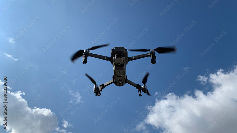 Latest technology RC camera drone or UAV (unmanned aerial vehicle) hovering on deep blue cloudy sky Latest technology RC camera drone or UAV (unmanned aerial vehicle) hovering on deep blue cloudy sky