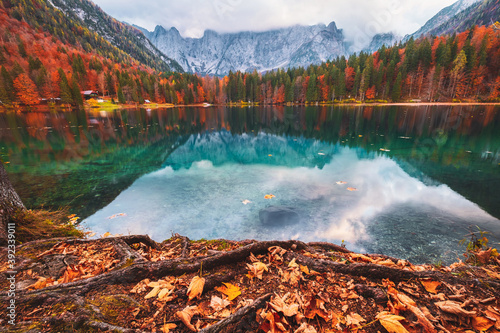 Lago di Fusine mountain lake in autumn colors and Mangart mountain in the background at sunset