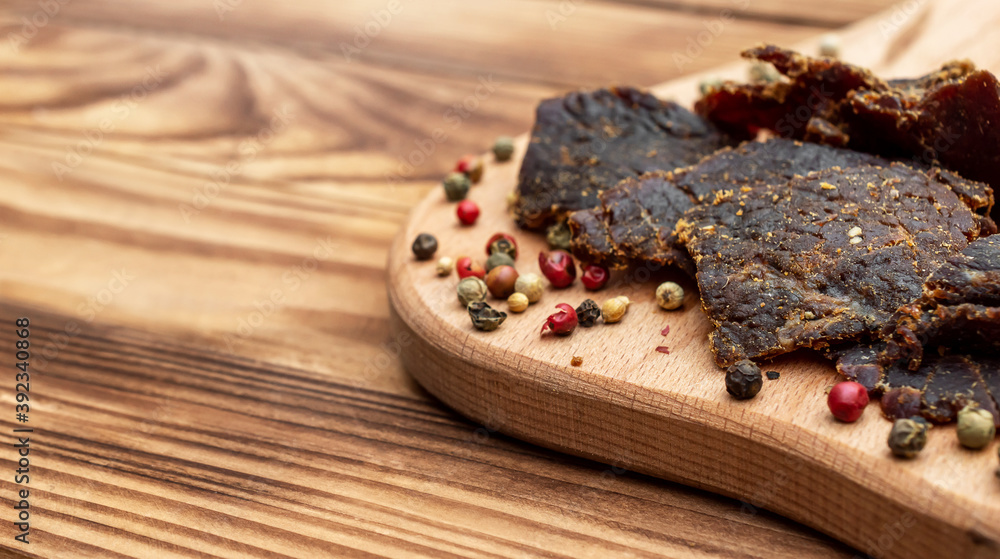 Fototapeta premium Cutting board with beef jerky and spices on wooden table. Close up.