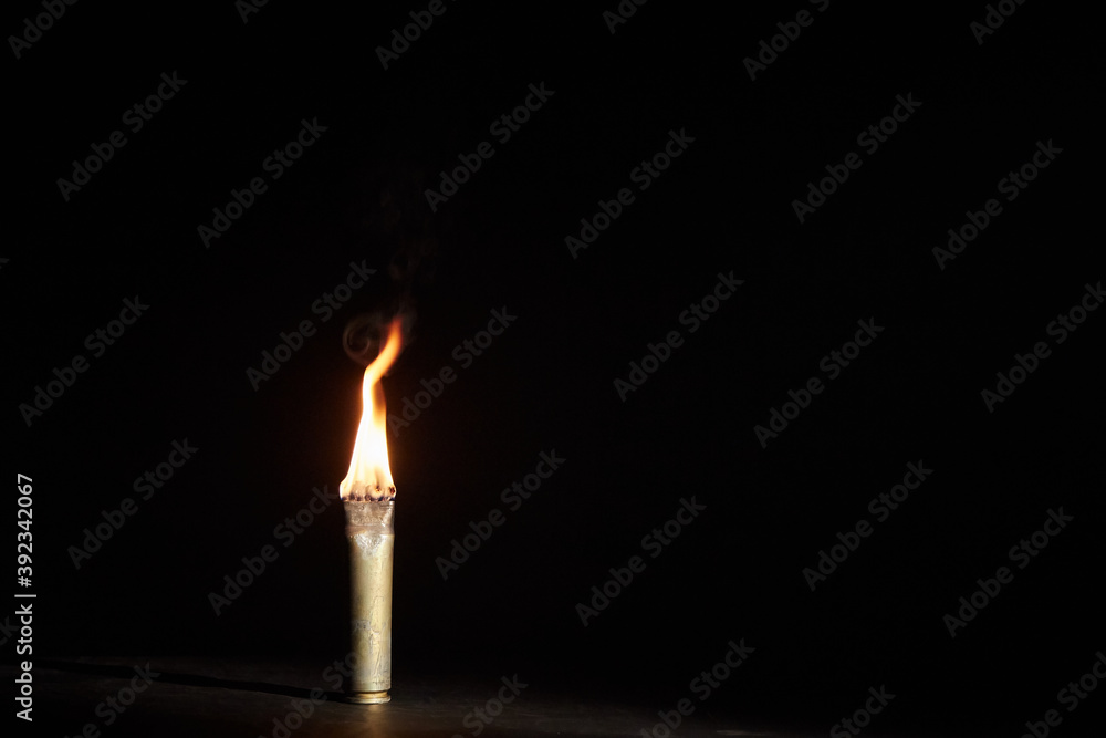 War candle. The candle burns in an empty sleeve. As a symbol of war and victims. Candle for remembering day. Located on black background. A candle used by the soldiers of the Second World War War candle. The candle burns in an empty sleeve. As a symbol of war and victims. Candle for remembering day. Located on black background. A candle used by the soldiers of the Second World War