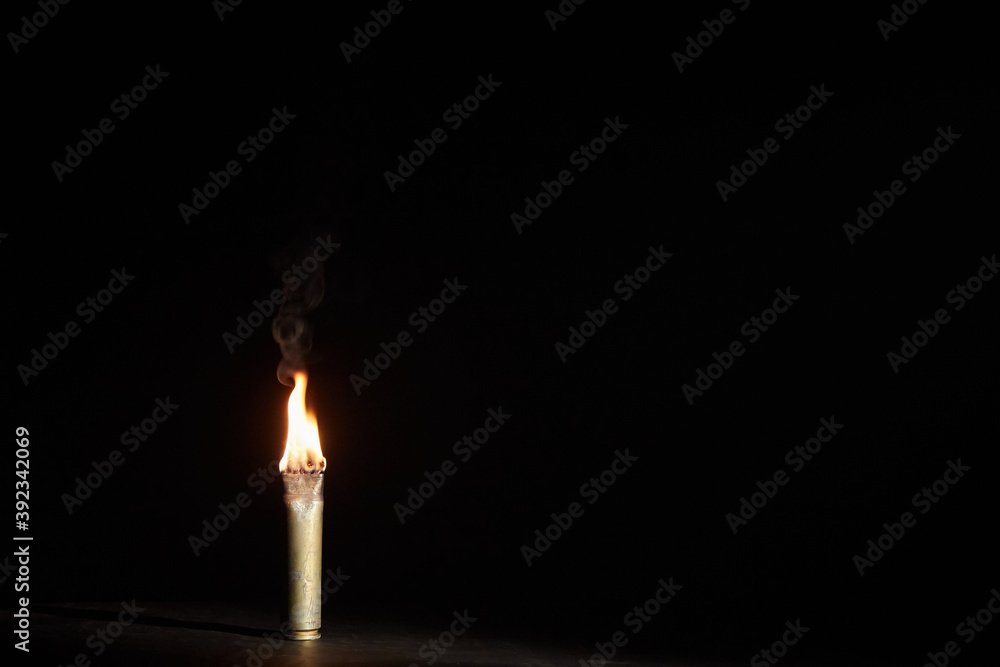 War candle. The candle burns in an empty sleeve. As a symbol of war and victims. Candle for remembering day. Located on black background. A candle used by the soldiers of the Second World War War candle. The candle burns in an empty sleeve. As a symbol of war and victims. Candle for remembering day. Located on black background. A candle used by the soldiers of the Second World War