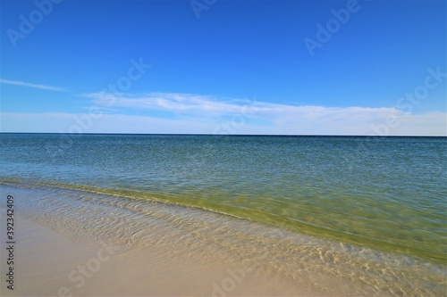 The seascape  a beautiful blank view from the coast of the Gulf of Mexico  calm ocean waters without waves over the horizon converge with a clear blue sky  in the foreground you can see the coast with