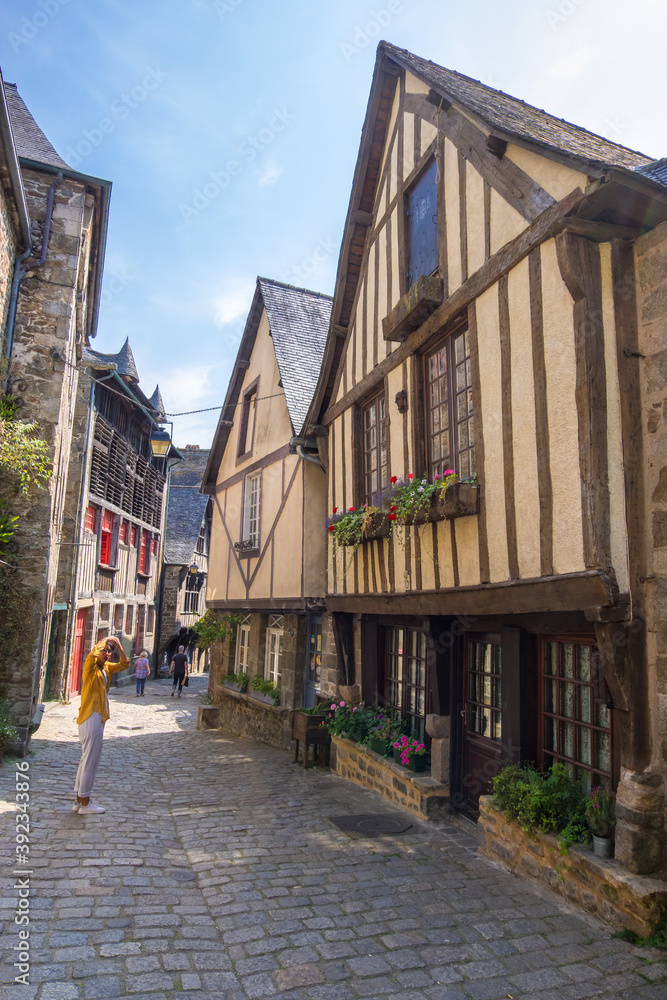 Fototapeta premium Dinan, France - August 26, 2019: View of historic colombage half-timbered and stone houses on the old cobblestoned street of Dinan, French Brittany