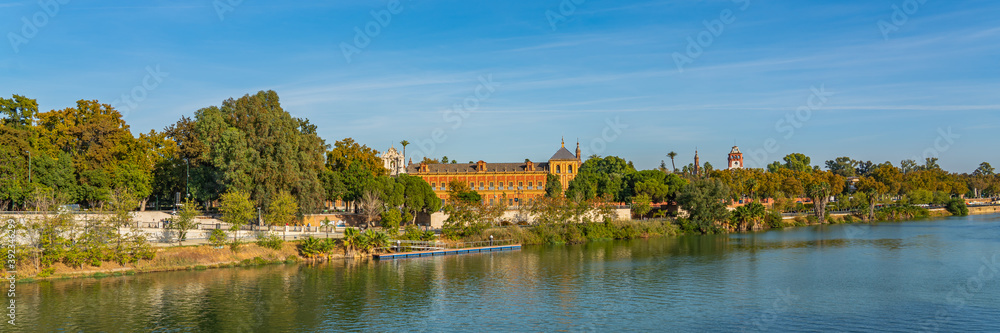 Historical Palacio de San Telmo in Baroque architecture on the green embankment of Guadalquivir river in Seville, panorama