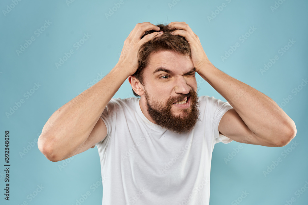 Bearded man in white T-shirt emotions gestures with hands displeased facial expression blue background Bearded man in white T-shirt emotions gestures with hands displeased facial expression blue background