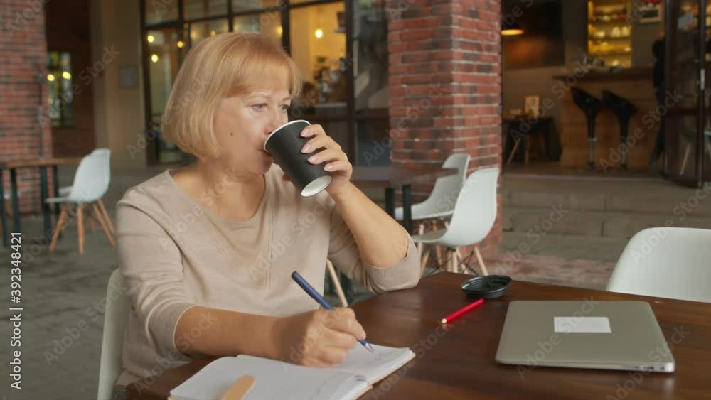 Female book writer drinks coffee and writes book in cafe Female book writer drinks coffee and writes book in cafe