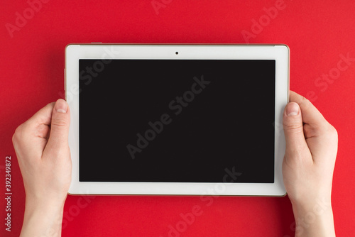 Technology development. Top above overhead view photo of female hands holding tablet isolated on red background with copyspace