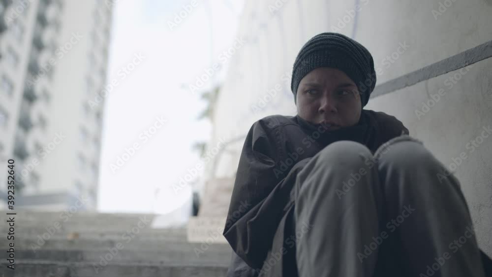 Desperate poor woman feeling cold, sitting on the stairs, social exclusion Desperate poor woman feeling cold, sitting on the stairs, social exclusion