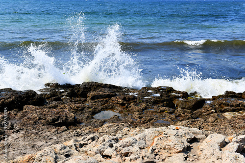 Beautiful bursts of foam waves on the seashore. White foam and bubbles beat against the rocky beach. Turquoise waves.