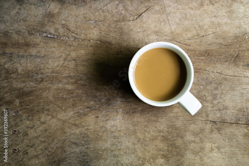 Top view of hot latte in white cup on old rustic wood table.