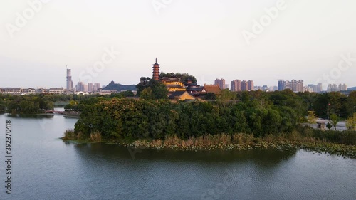 Aerial drone flying view of Jinshan Temple with symbolic Cishou Pagoda & cityscape behind over Jinshan Lake in Zhenjiang, Jiangsu, China. First established in 4th CE. Heritage & tourist attraction. photo