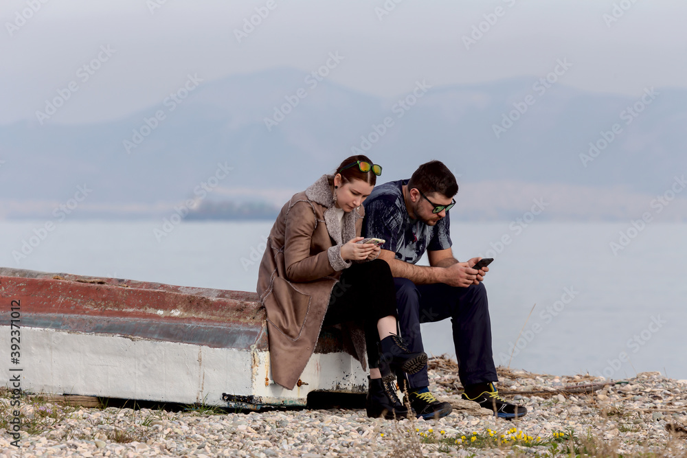 Young couple on the beach with phones